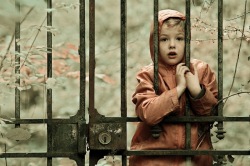 Il était une fois ... (Photo, avec un traitement technicolor, d'une enfant habillée comme le petit chaperon rouge, emprisonnée derrière une grille.)